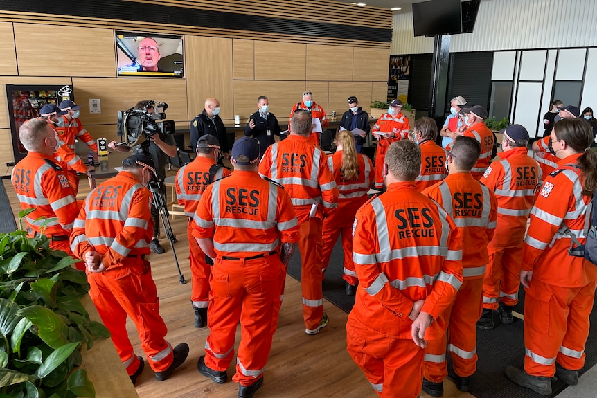 a group of SES volunteers with orange overalls gathering in a room