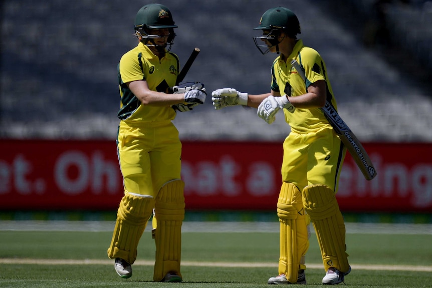 Australia's Alex Blackwell (L) and Elyse Villani bump gloves at the change of innings.