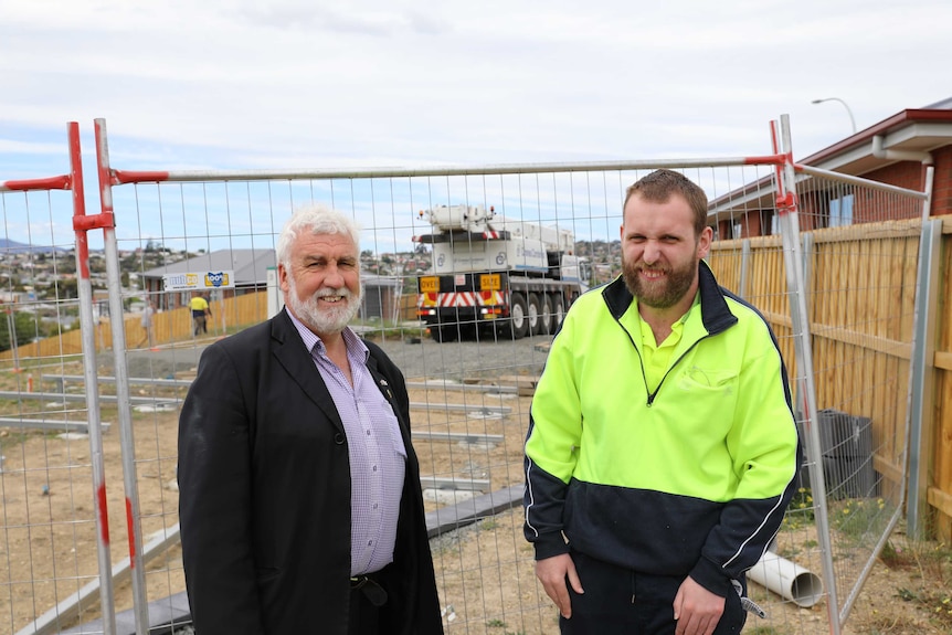 Father and son Bob and Jack Gordon stand in front of a fence at the Supported Affordable Accommodation site in Glenorchy.