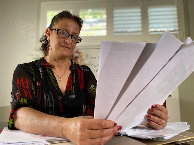 A middle aged woman looks at documents  at her kitchen table 