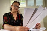 A middle aged woman looks at documents  at her kitchen table 