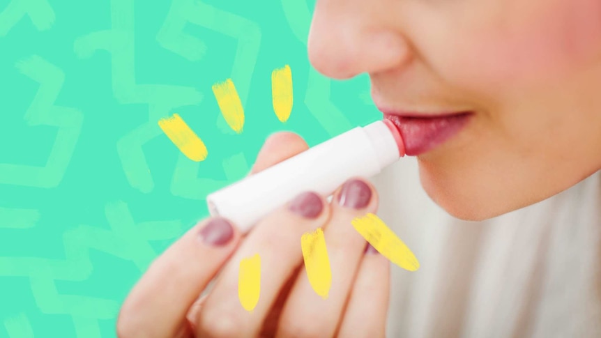 Close up of woman applying lip balm for a story about how to treat dry, cracked lips in winter.