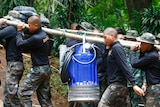 Soldiers carry pump to help drain rising flood water