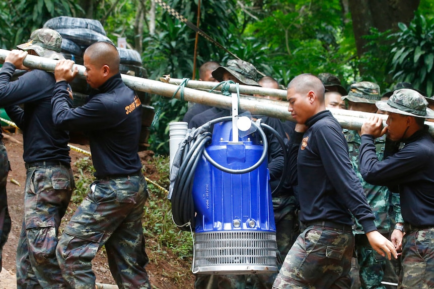 Soldiers carry pump to help drain rising flood water