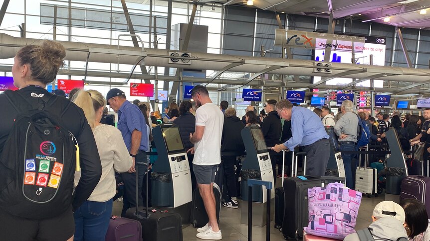 People crowded around and liked up at check-in terminals at Rex Airlines departures area at Sydney Airport