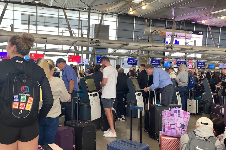 People crowded around and liked up at check-in terminals at Rex Airlines departures area at Sydney Airport