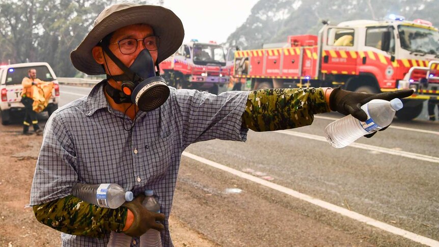 A man hands out drink bottles in a spooky air mask