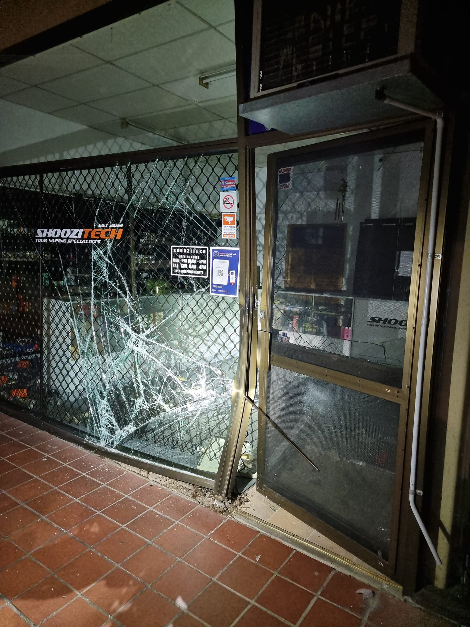 A smashed shopfront, with the door frame pulled out of shape.