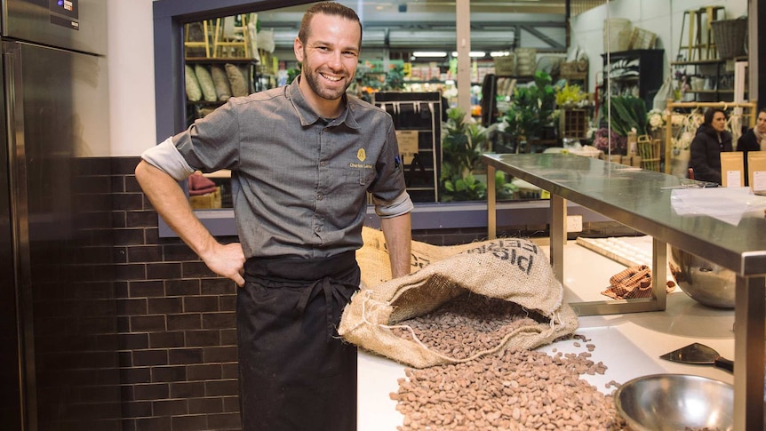 Atypic Chocolate's Charles Lemai in his South Melbourne Market kitchen, alongisde a spilled bag of cocoa beans.