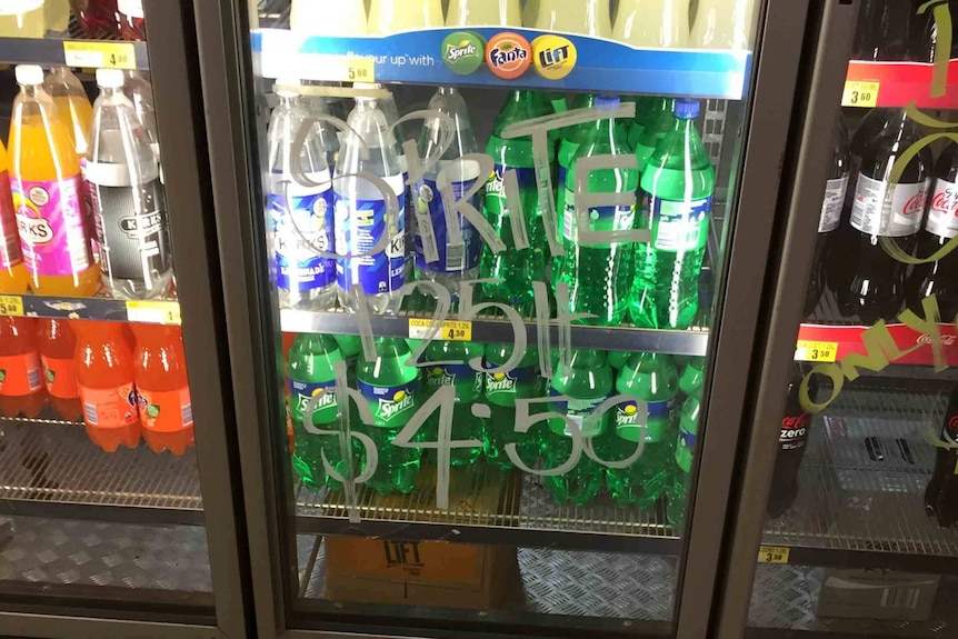 fridge of drinks with hand written sign saying $4.50 cost