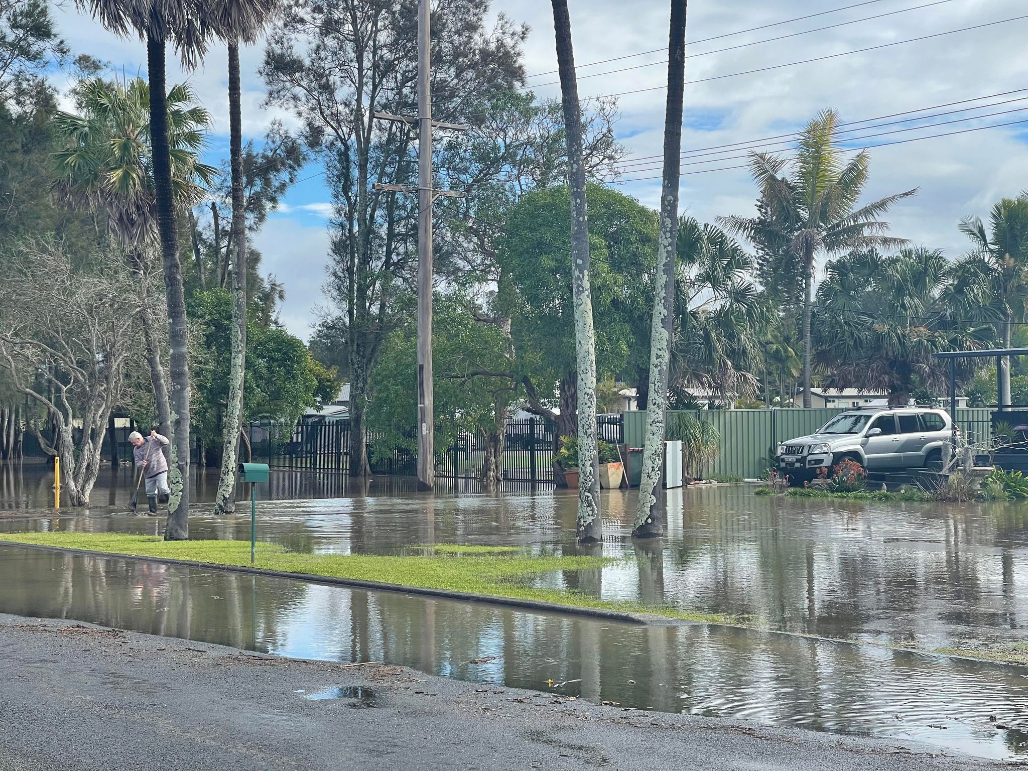 floodwaters around a home in Tuncurry with a man sweeping up