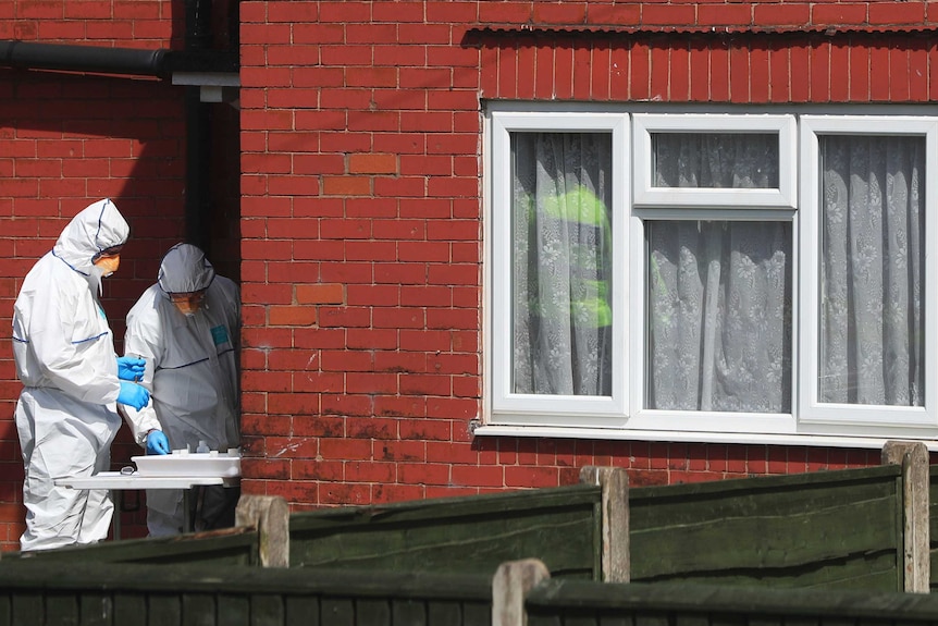 Police forensic investigators wearing white disposable suits and blue gloves search the property of Salman Albedi