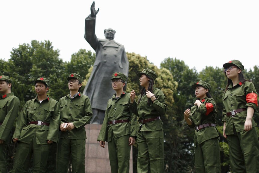 Students in military uniforms stand in front of a statue of late Chinese leader Mao Zedong.