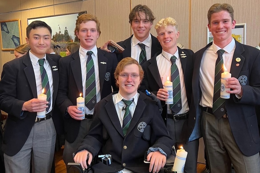 Six boys in school uniform, including one in front in a wheelchair.