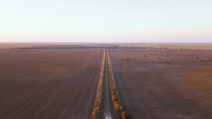 A drone photo of a long, straight road across dust plains.
