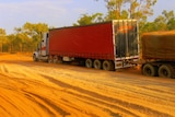 a road train bogged in dust on an unsealed road