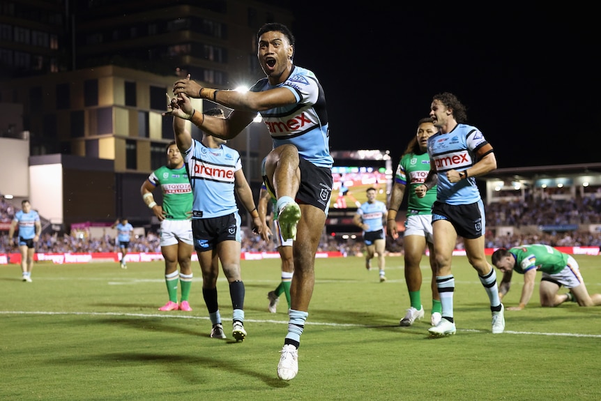 A Cronulla NRL player celebrates after kicking the ball into the crowd.