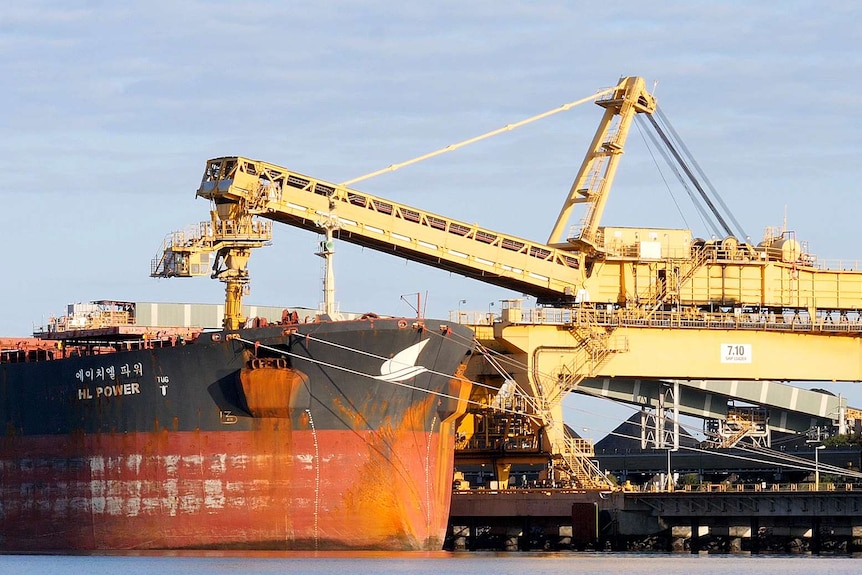 A freight ship is loaded with coal at a port.