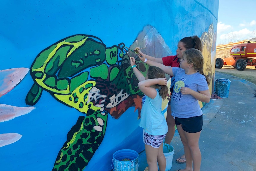 Children paint a mural on a water tank in Bowen.