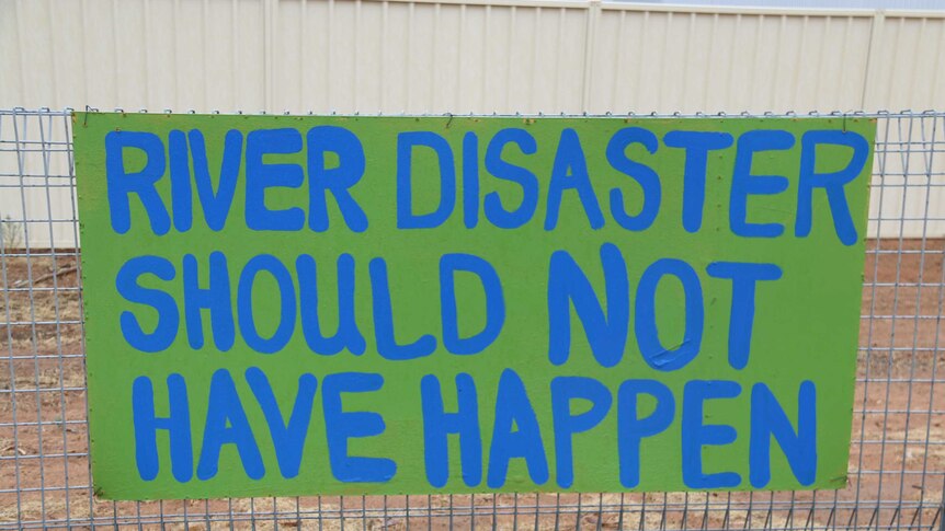 A handwritten sign readers "river disaster should not have happened"