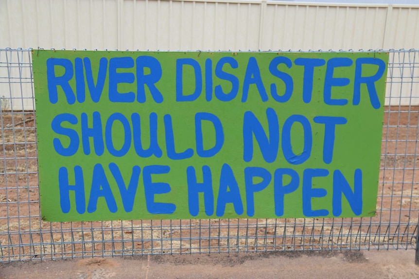 A handwritten sign readers "river disaster should not have happened"