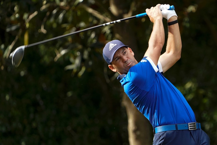 A golfer watches his shot from the tee on the opening hole of a tournament.