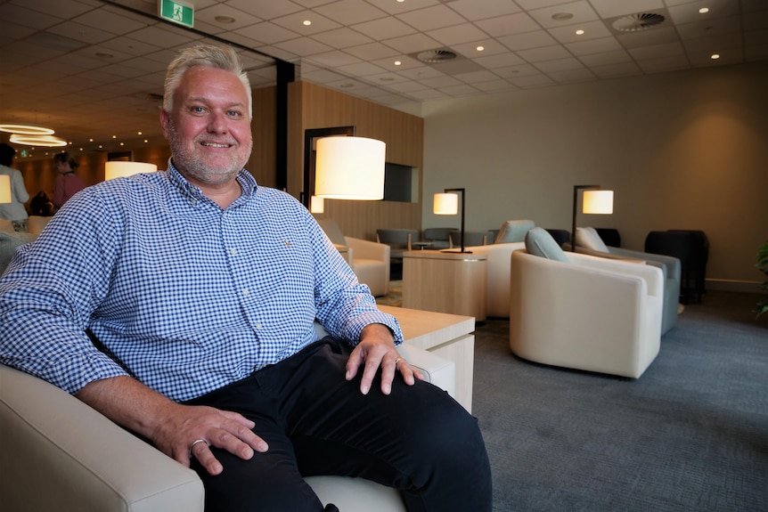 Man sitting in an airport lounge chair.