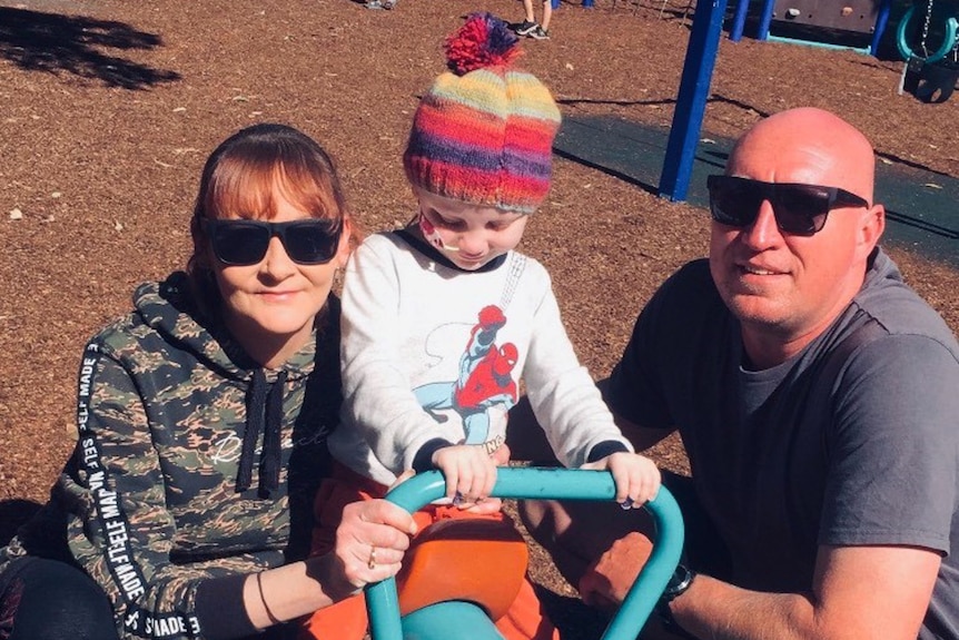 Mum and dad with their daughter on playground equipment.