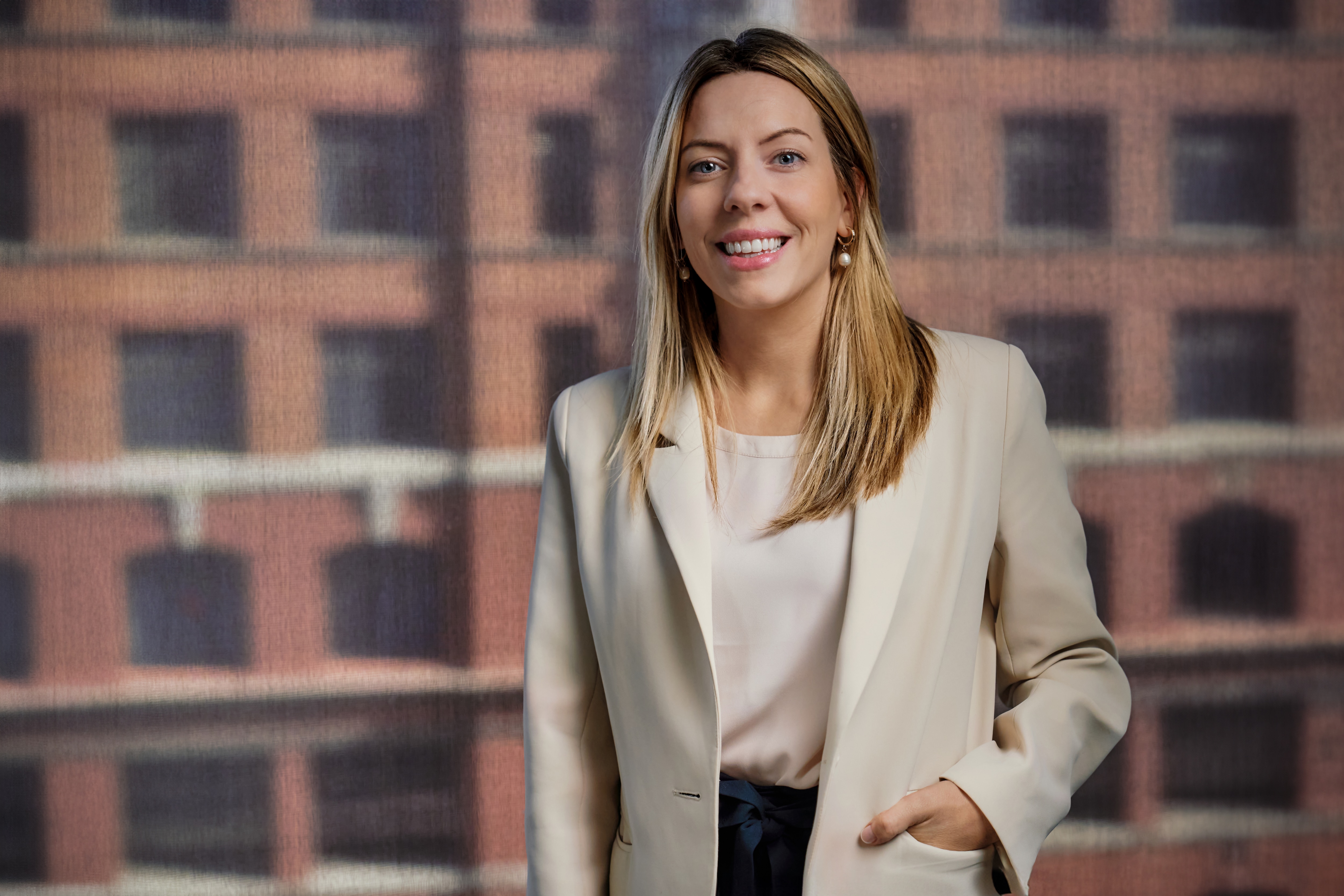 Una mujer vestida de negocios sonríe a la cámara en una oficina.