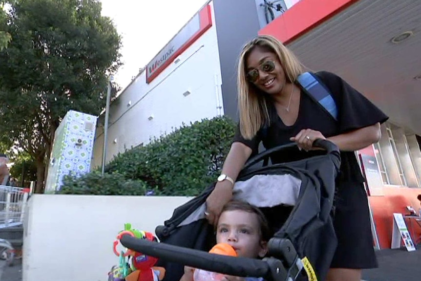 Delrissa Marciano touches her son's cheek while pushing him along the street in the pram