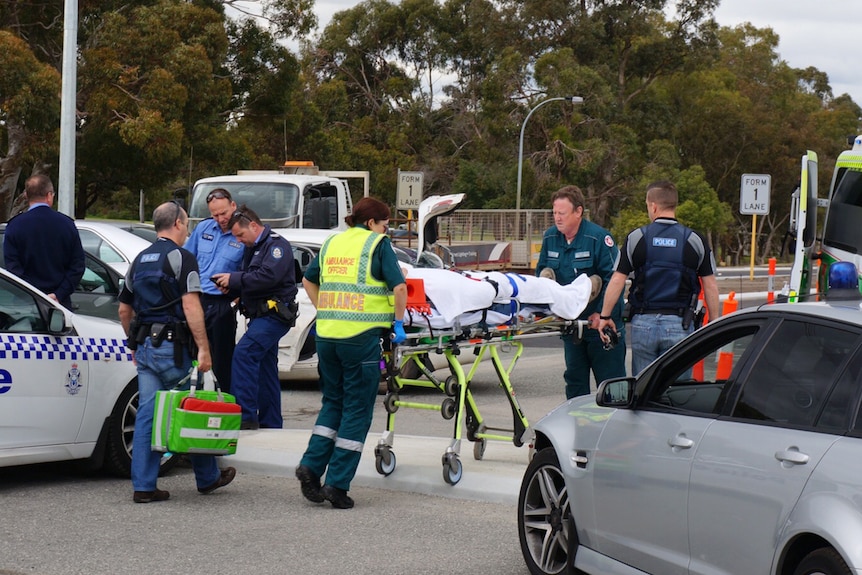 Police officer is stretchered into an ambulance after police chased an escaped prison though southern Perth suburbs 15 August 2016