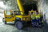 An electric vehicle at the opening of an underground mine with staff around.