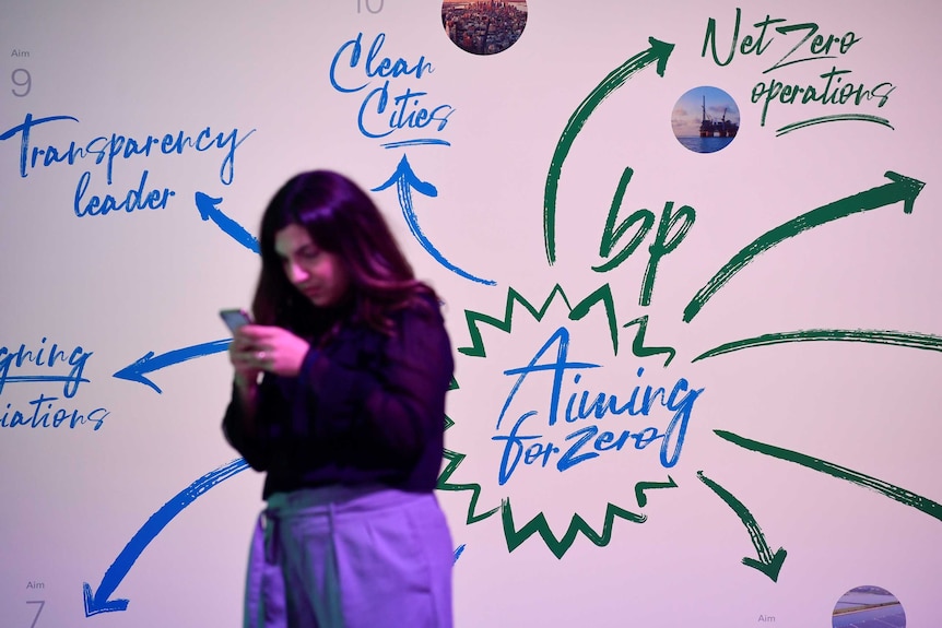 A woman uses her mobile phone in front of signage at a BP event.