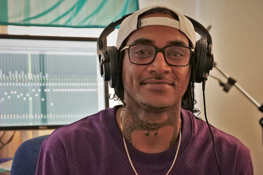 A man wearing head phones sits in his music studio