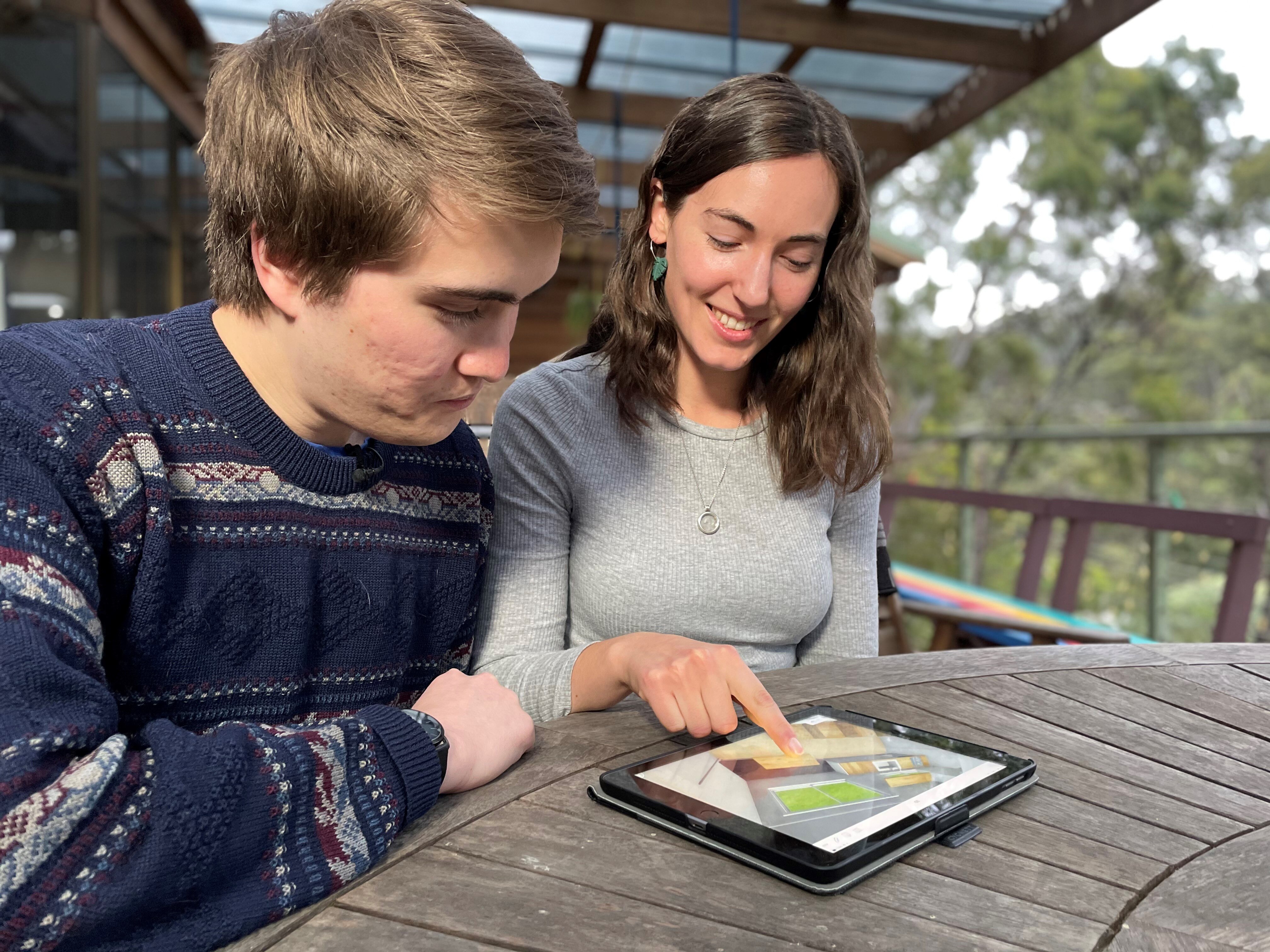 Jonty Dalton and Lucy Smith sit at a wooden table, looking at an iPad.