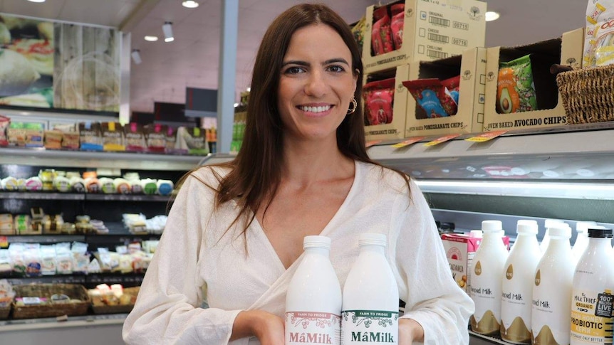 Tegan Scates from MaMilk holds two bottles of cold pressed hemp milk at a Brisbane supermarket.