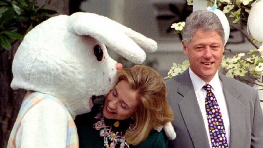 Former US first lady Hillary Rodham Clinton is kissed by the Easter bunny, as former president Clinton looks on.