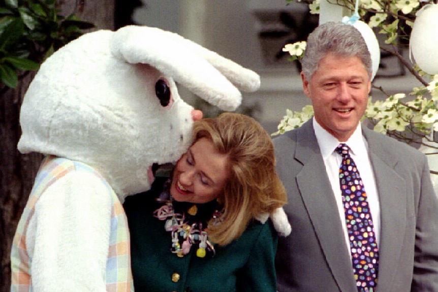 Former US first lady Hillary Rodham Clinton is kissed by the Easter bunny, as former president Clinton looks on.