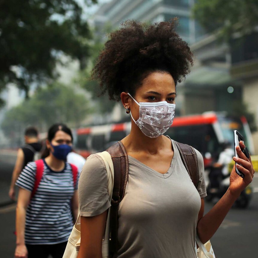 A woman walking with a face mask.