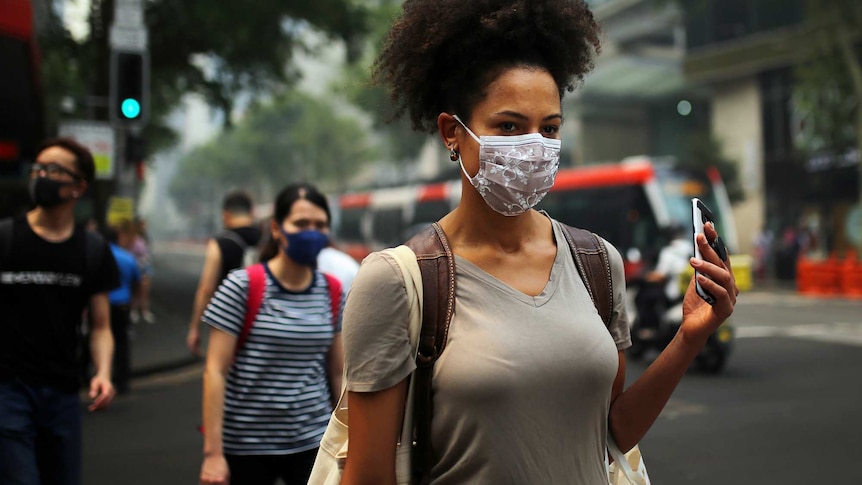 A woman walking with a face mask.