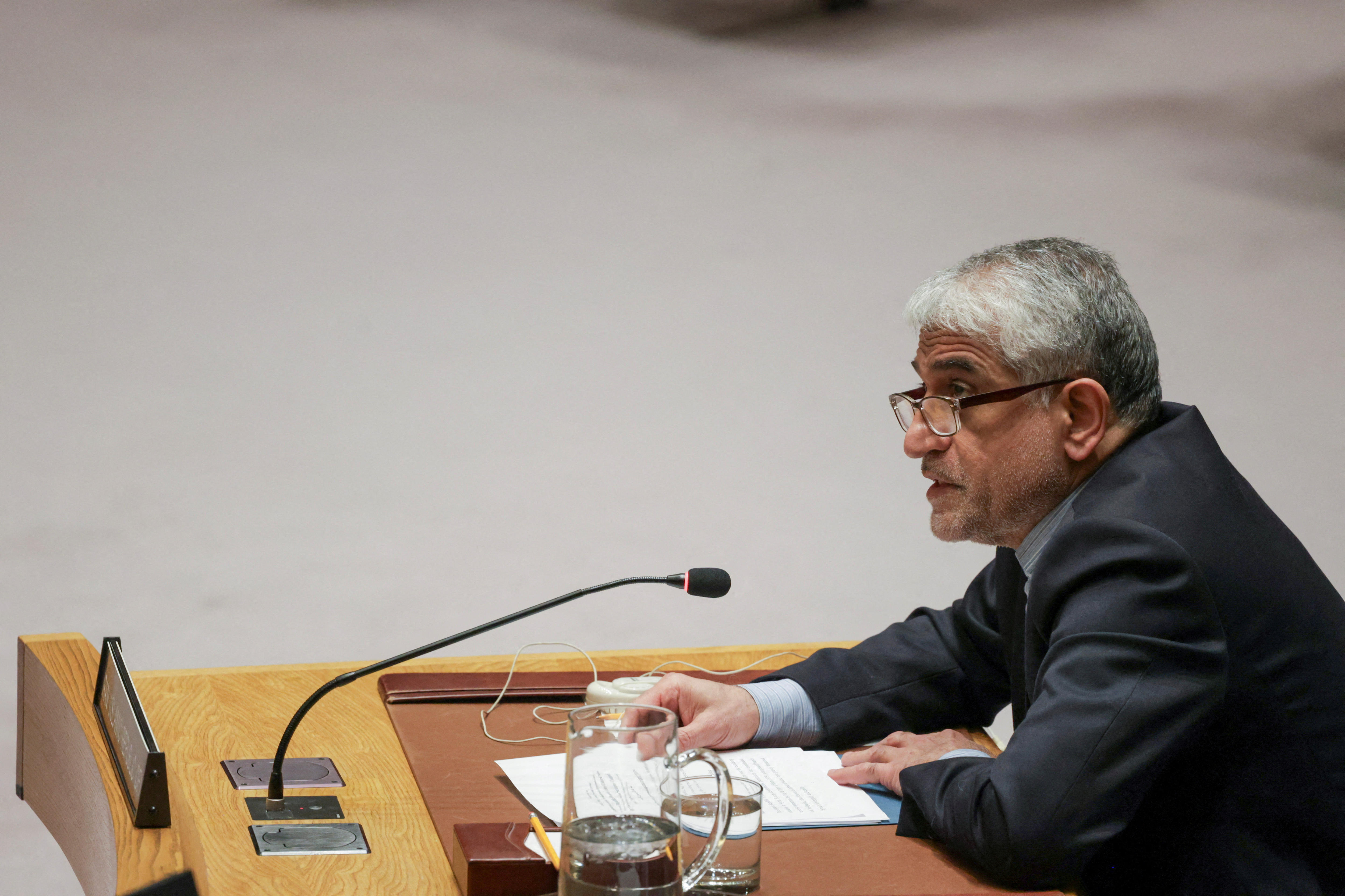 Amir Saeid Iravani sits at a desk, speaking into a microphone