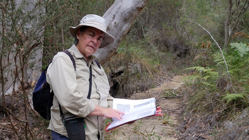 Julie Sheppard holds documents while standing on a dry creek bed in the Cordeaux Dam catchment area.