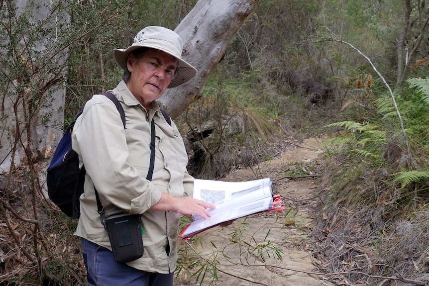 Julie Sheppard holds documents while standing on a dry creek bed in the Cordeaux Dam catchment area.