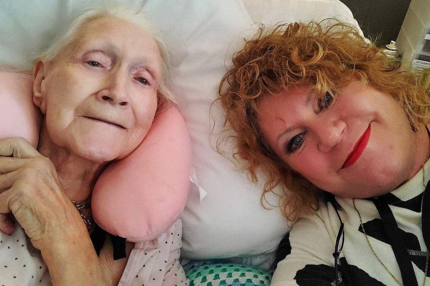 A daughter smiling with her mum in a hospital bed.