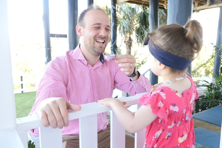 Tim holds a toy tea cup out to Charlotte