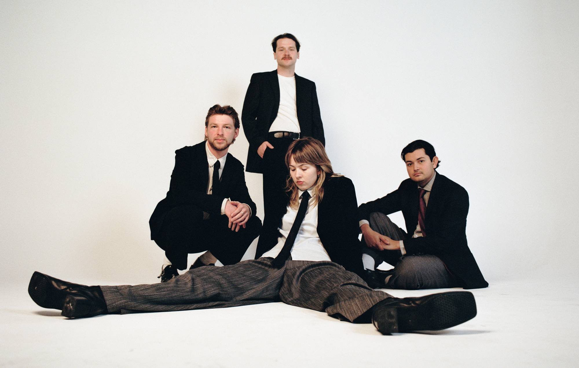 Four people in suits - three men and a woman - pose for a photo against a plain backdrop. 