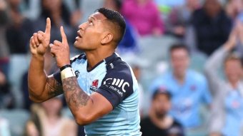 In a blue jersey, Folau gestures with his fingers and looks up.