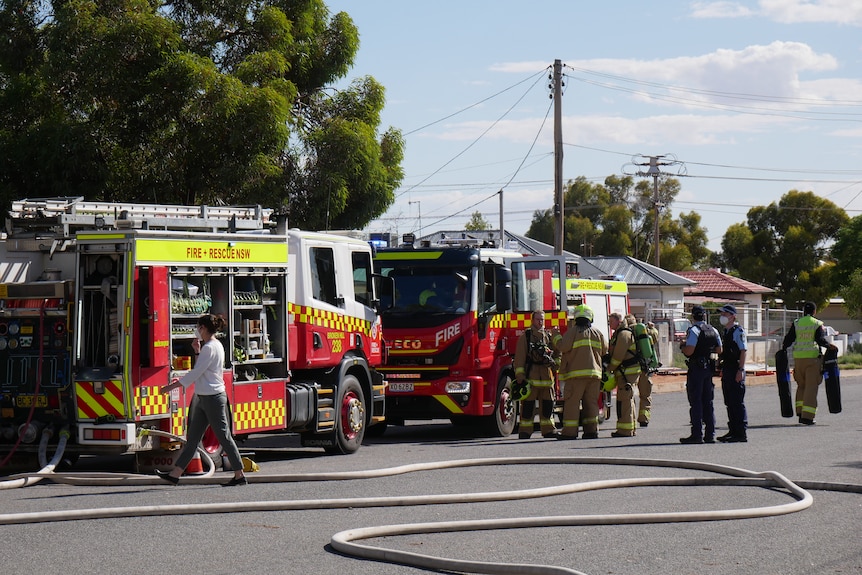 Police, firefighters and ambulance officers at the scene of a house fire.