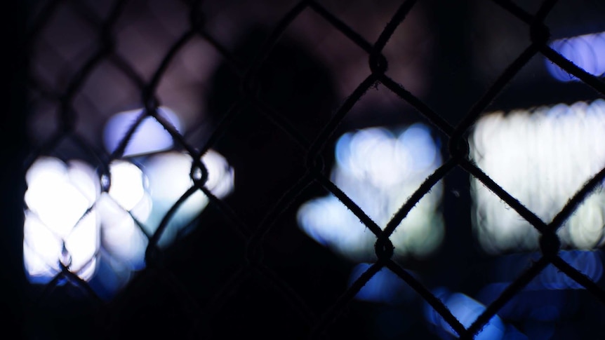 A shadowed figure behind a fence