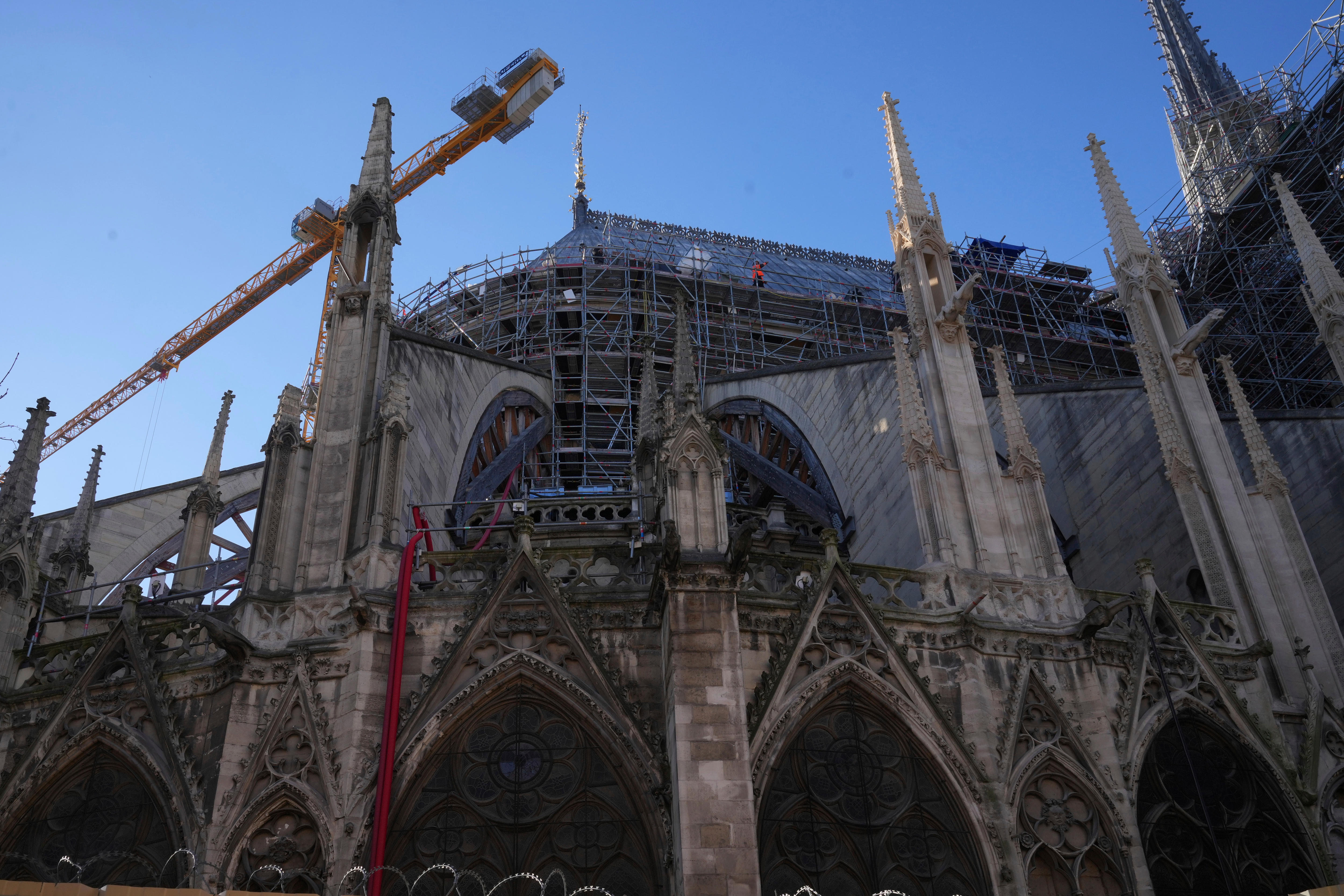 A person in orange hi-vis walks on scaffolding around the Notre Dame cathedral